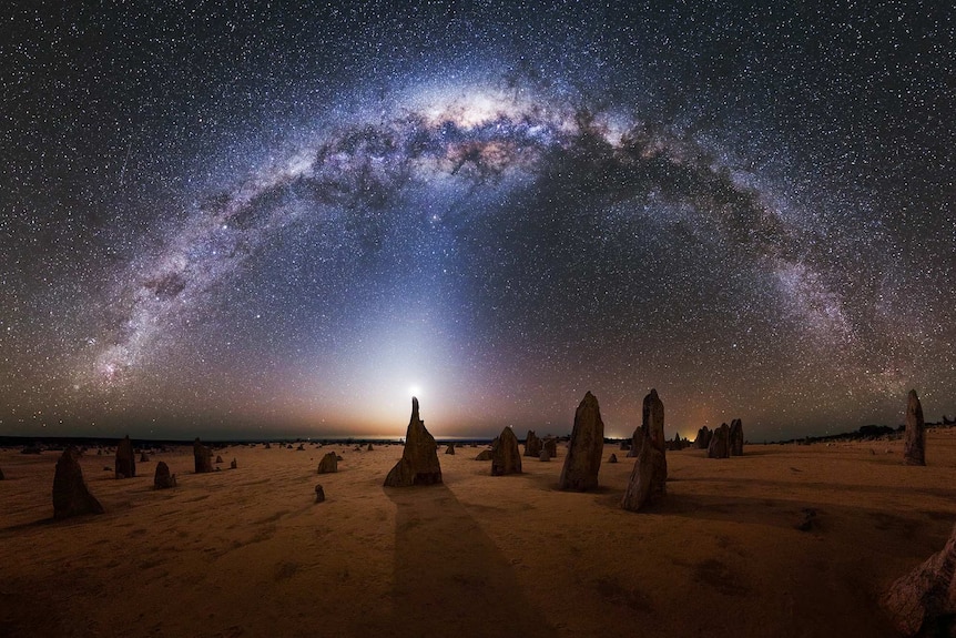 A wide shot of the Milky Way visible in a starry night sky with the Pinnacles below.