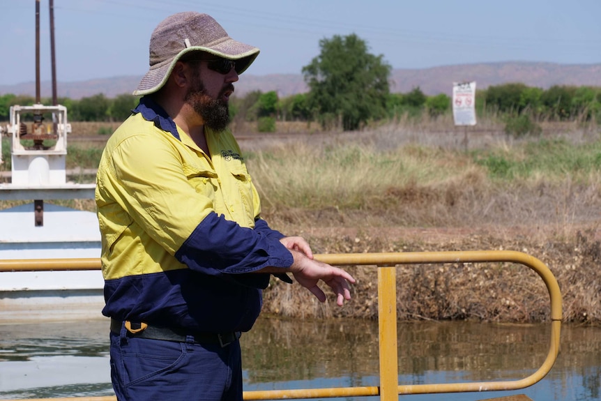 Man in high vis clothing standing in front of irrigation channel