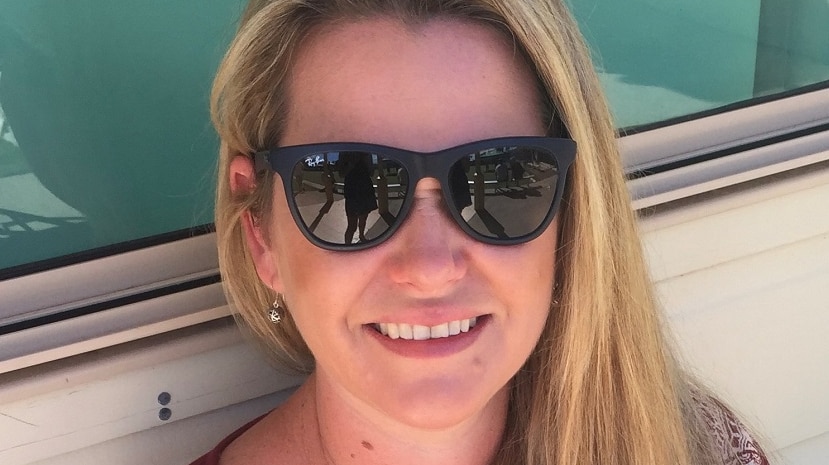 A smiling  lady with long blonde hair wearing sunglasses.