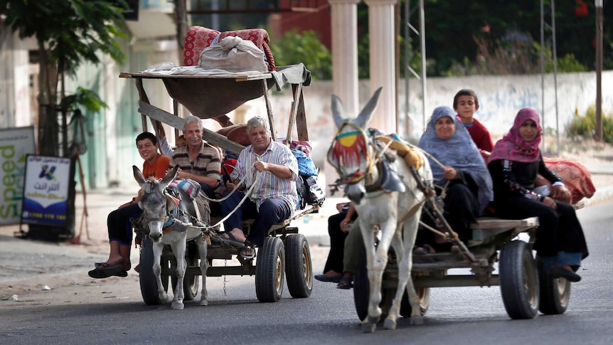 Palestinian families travel to a UN school in Gaza City to seek shelter after evacuating their homes.