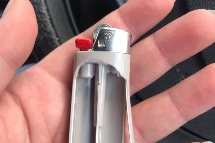 A hand holds a Bic-style lighter that appears to have exploded.