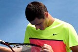 Bernard Tomic looks at his racquet