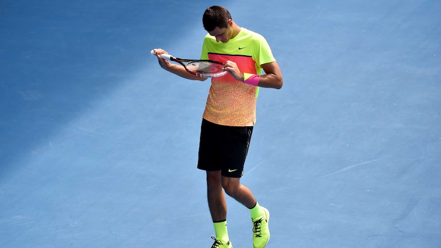 Bernard Tomic looks at his racquet