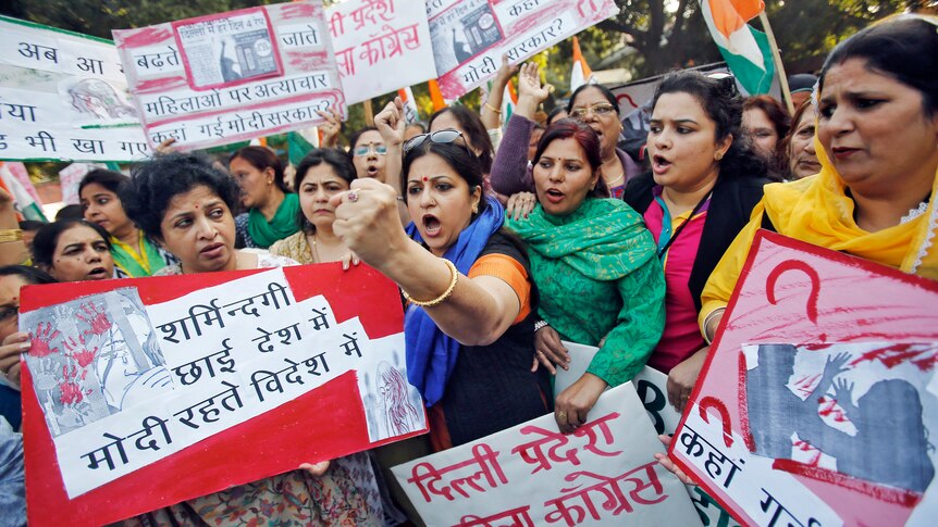 Women protest, holding placards