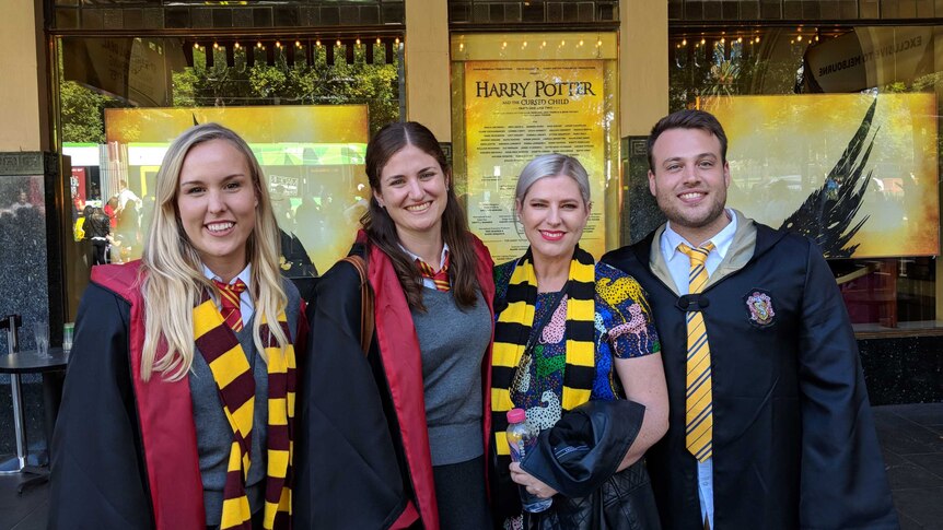 Four people dressed in Hogwarts robes standing out the front of a theatre