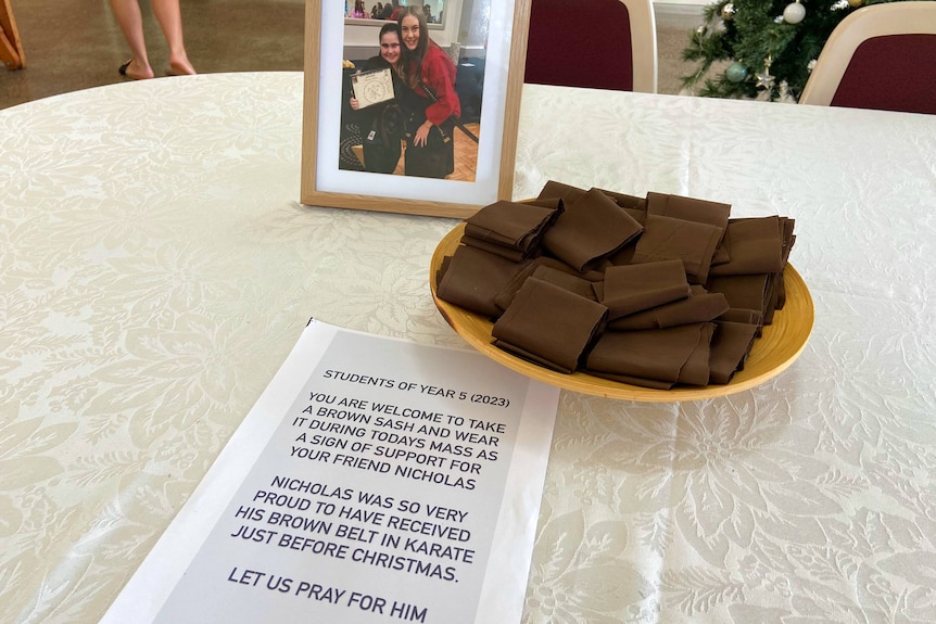 A photo of a boy next to a plate of brown sashes and a letter on a table