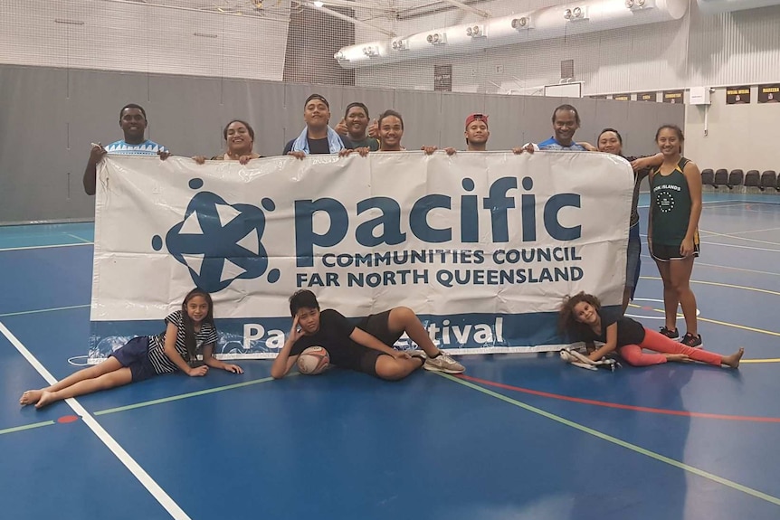 A group of people hold a banner reading 'Pacific Communities Council Far North Queensland'