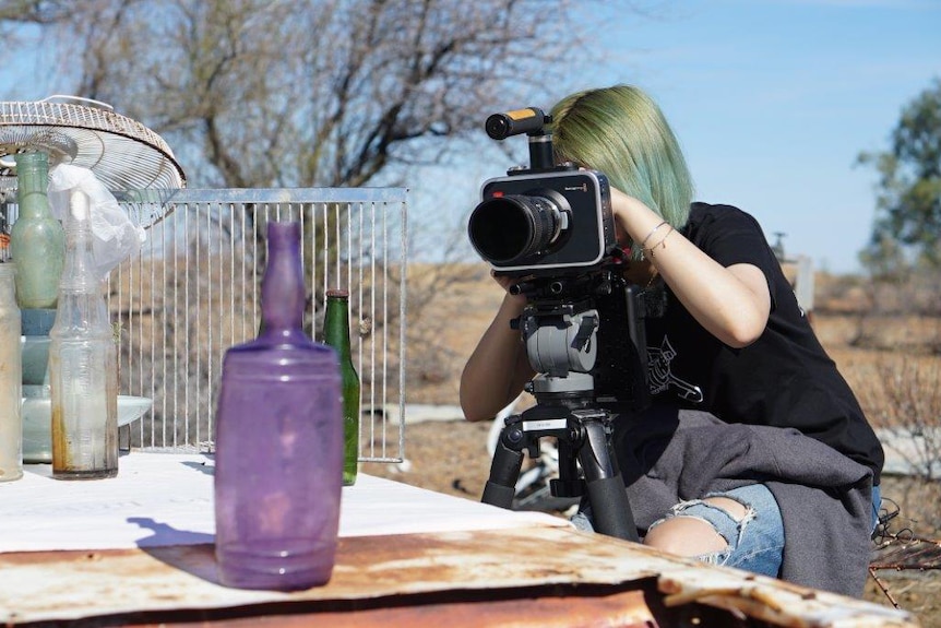 Student behind a camera practises filming glass bottles in Winton.