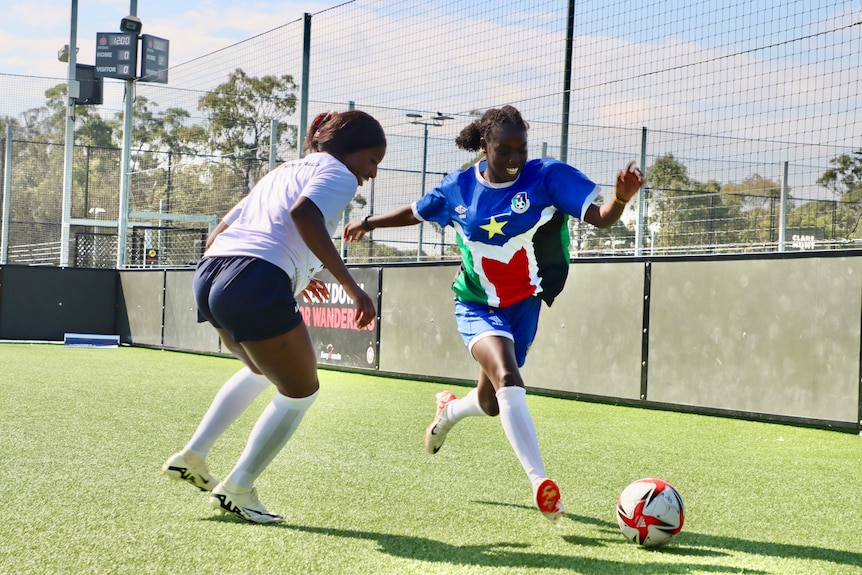 A young African soccer player dribbles the ball past an opponent.