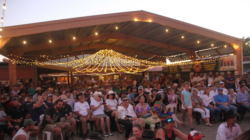 a crowd of people in a shed under fairy lights
