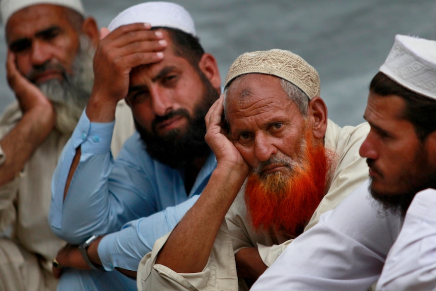 Men with long beards sit in the street.