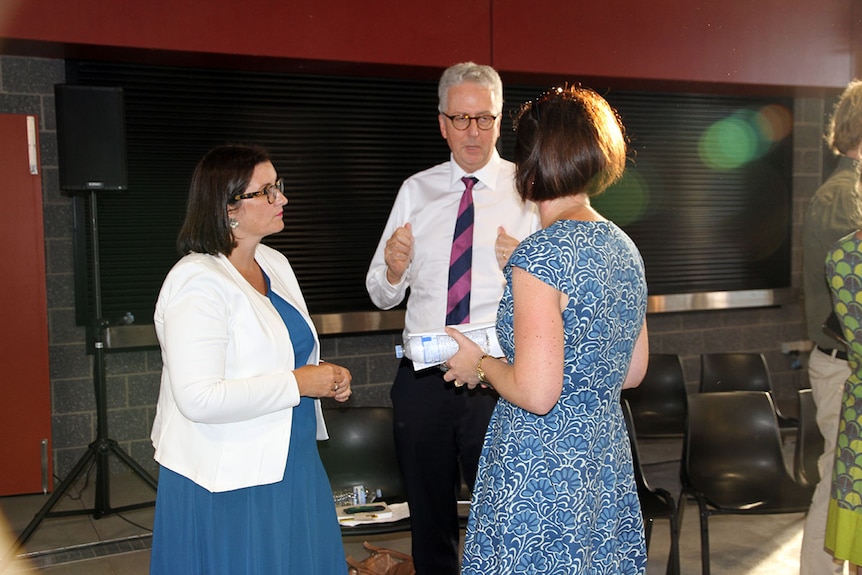 A man and two women talking at a school meeting