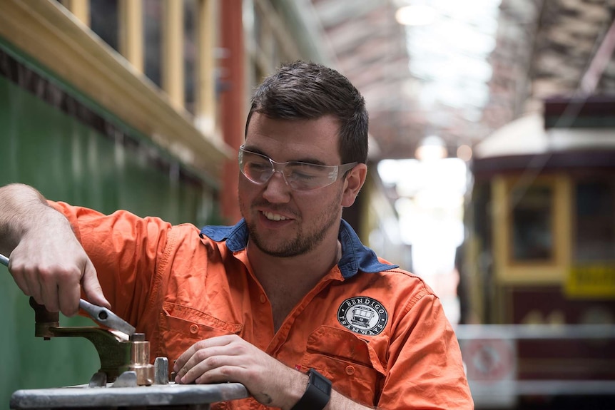 A man wearing safety glasses holds a shifter in a workshop