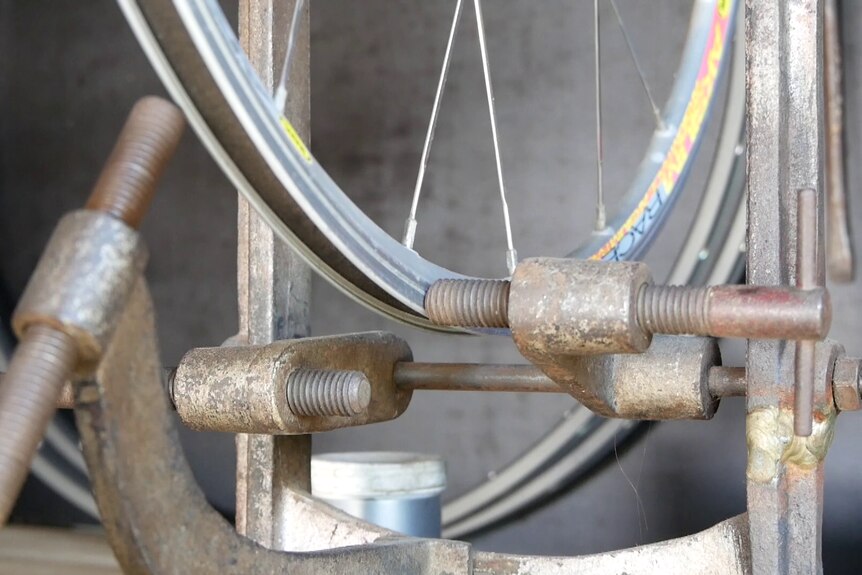 A wheel spins in a an antique bike clamp from Belgium.
