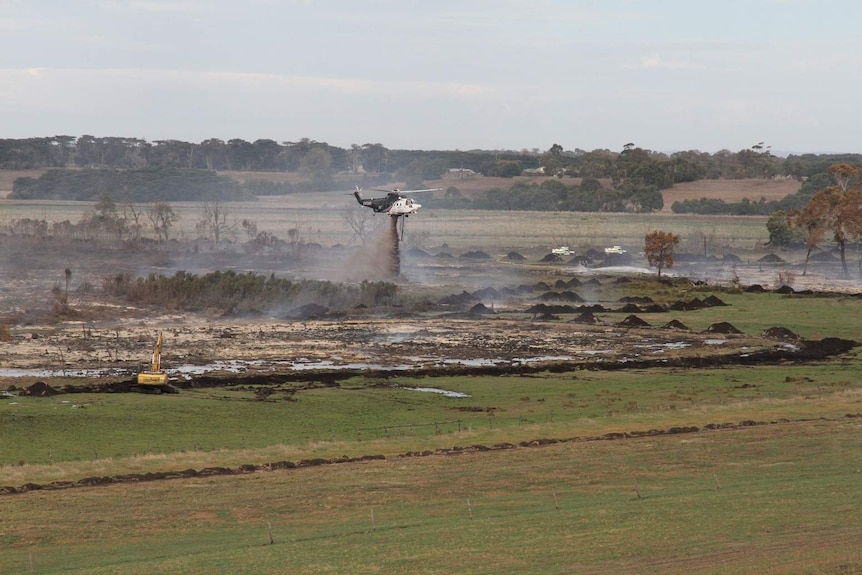 A helicopter drops water on a peat fire