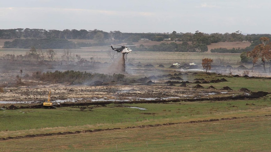 A helicopter drops water on a peat fire