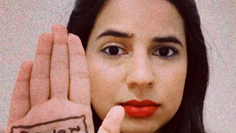 A woman shows her right palm that has "power to the people" written on it.