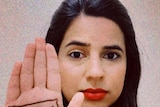 A woman shows her right palm that has "power to the people" written on it.