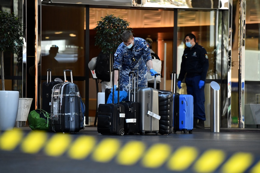 a man outside a hotel picking up luggage