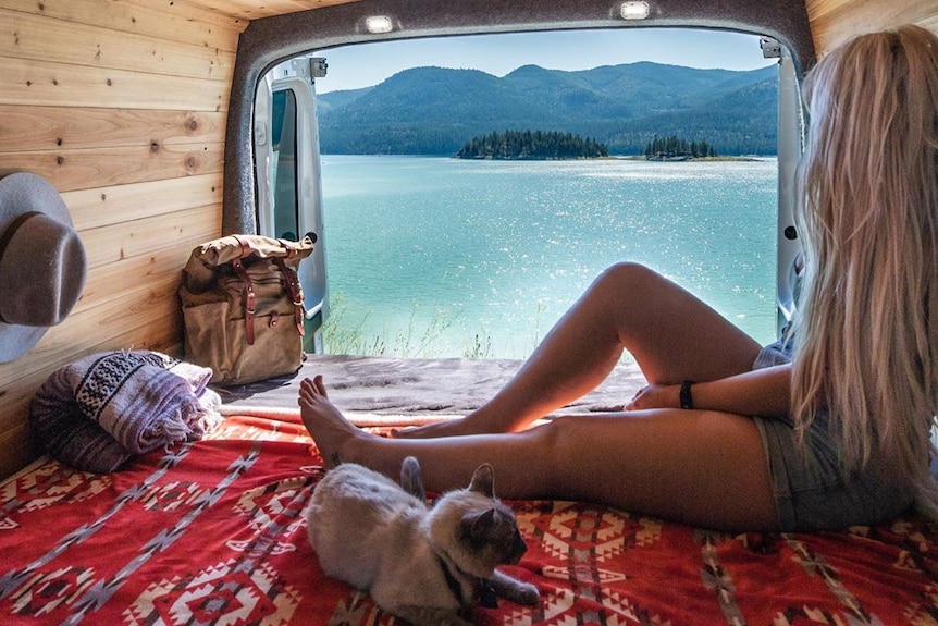 A woman looks out the back of her van.