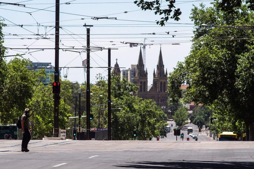 An empty main road with tram power lines above and a cathedral and bus in the background