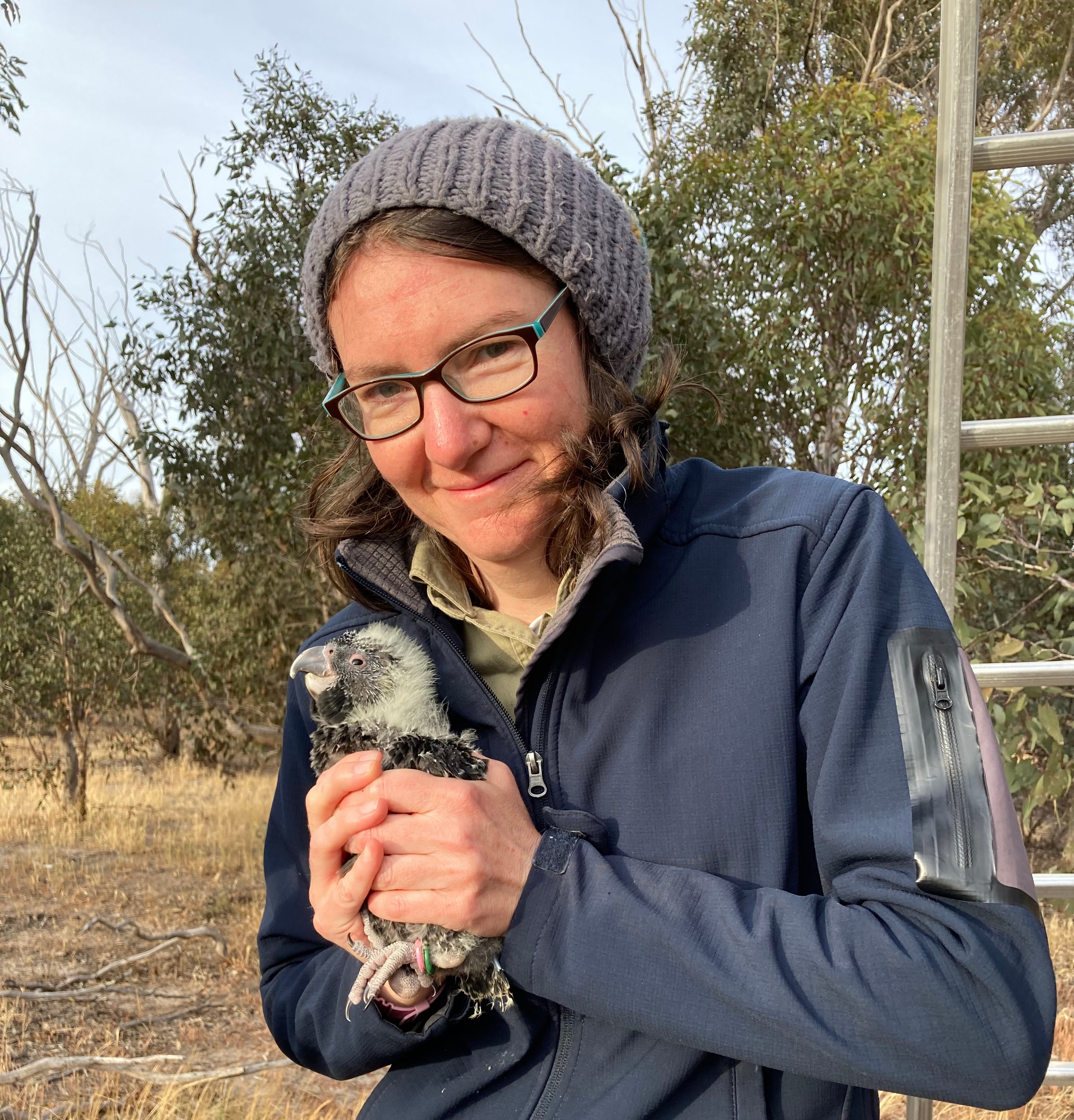 Zoe Kissane smiles and holds a juvenile bird