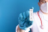 Doctor wearing latex gloves holds a covid-19 antigen test.