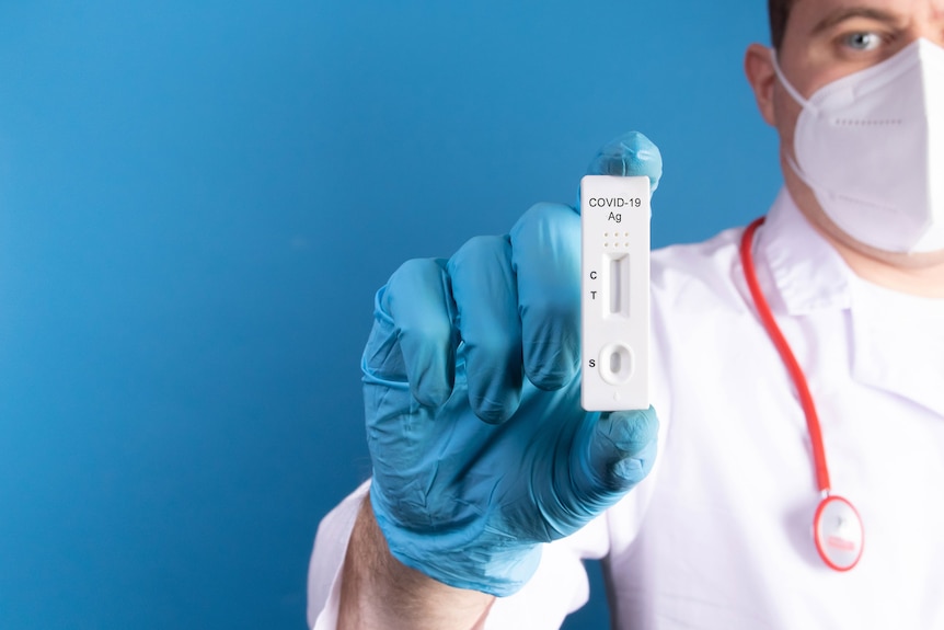 Doctor wearing latex gloves holds a COVID-19 rapid antigen test.