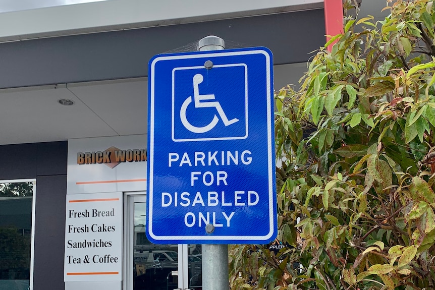 A blue street sign that says "parking for disabled only".