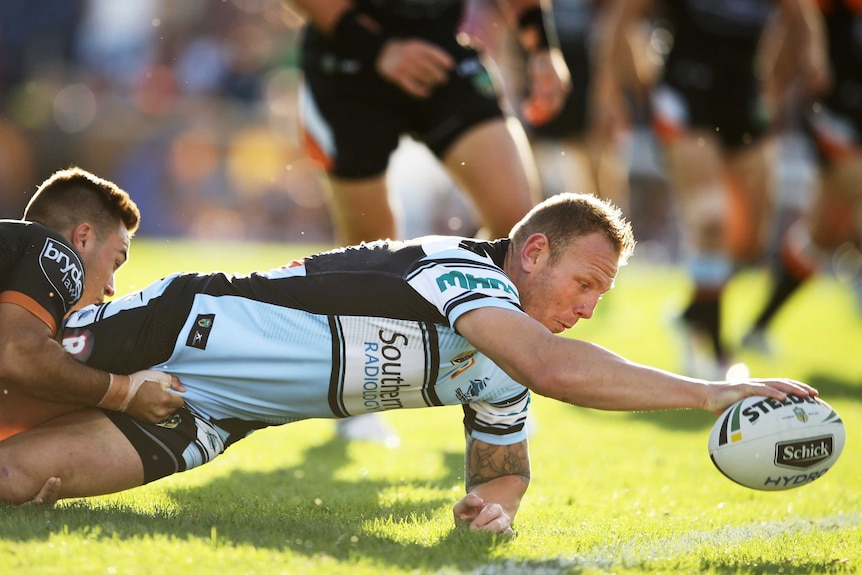 Desperate effort ... Luke Lewis reaches out to score a try for the Sharks against the Tigers