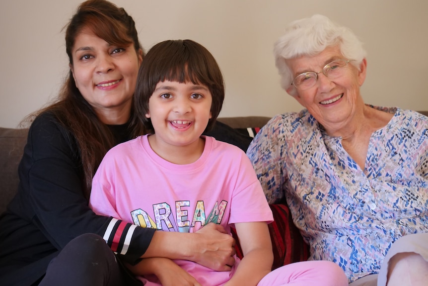 A woman and child sit next to an elderly woman smiling.