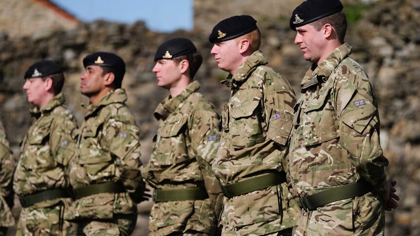 A line of soldiers in berets and camouflage fabric uniforms