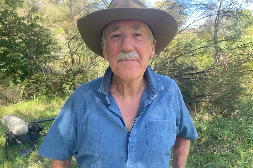 Photo of an older man standing in front of water.