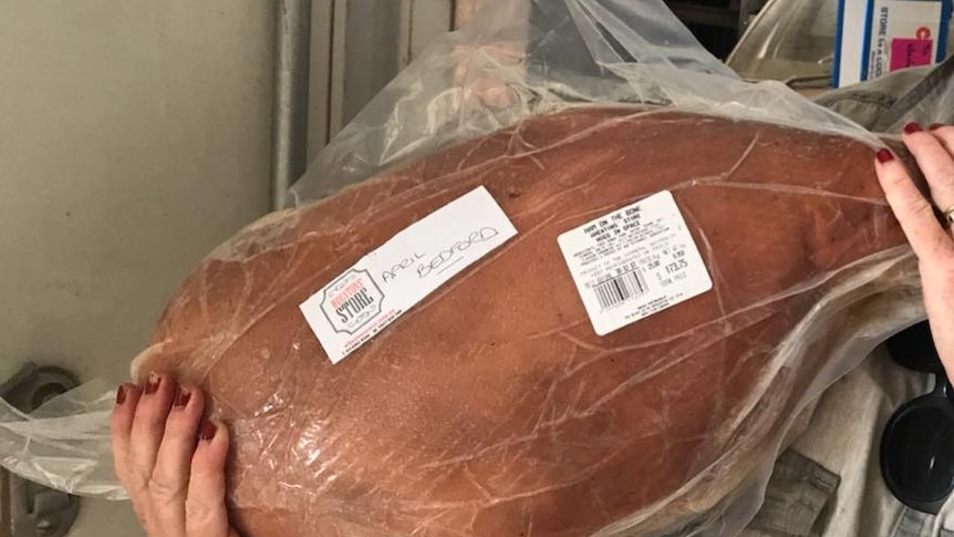 Jo Wheaton holding up one of their plastic wrapped Christmas hams