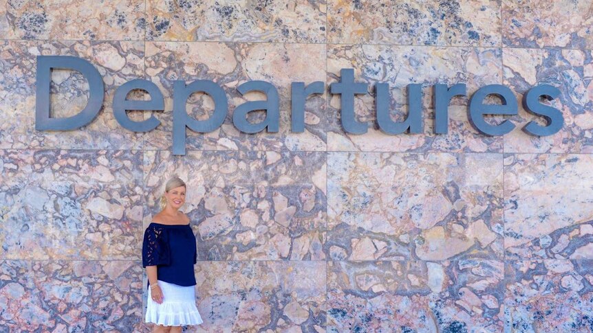 Woman standing out front of the departures sign.