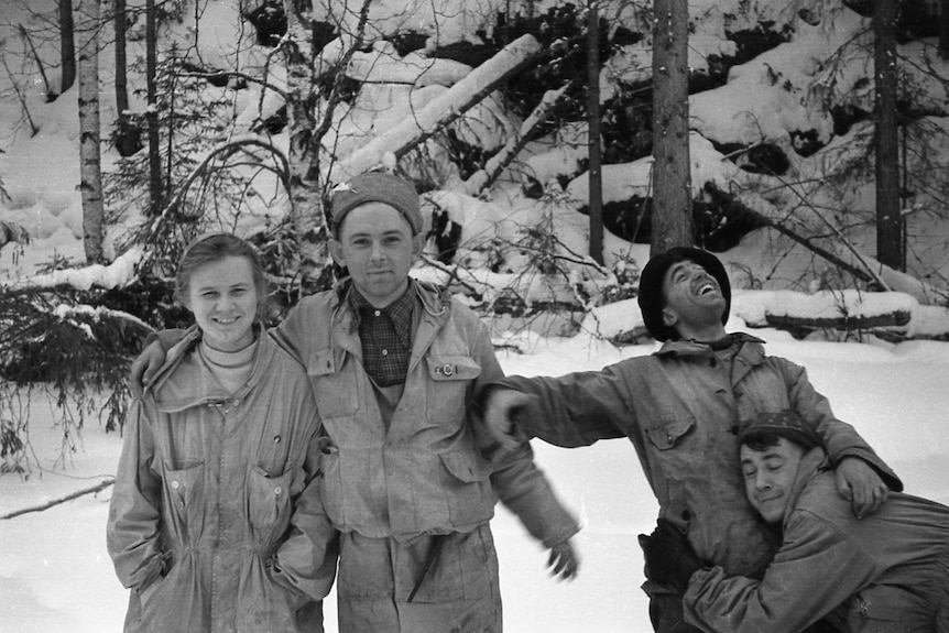 A black and white image of a young woman and three men in the snow