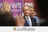 Mr Shorten standing in front of signs, pointing to a crowd.