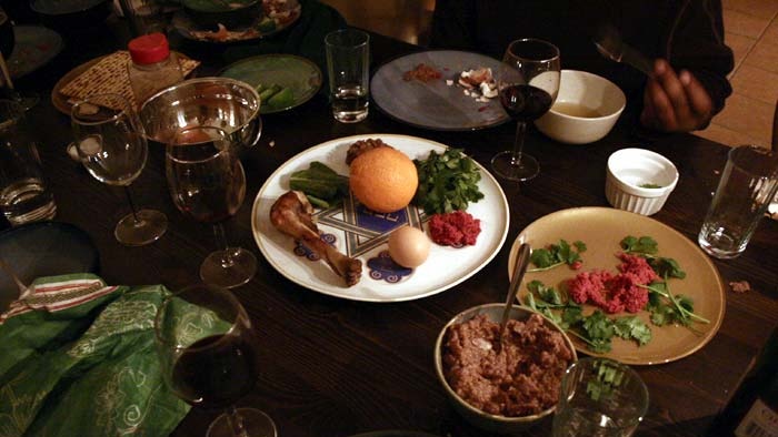 A table set for the Passover seder meal, with traditional foods on a central platter, side dishes and wine.
