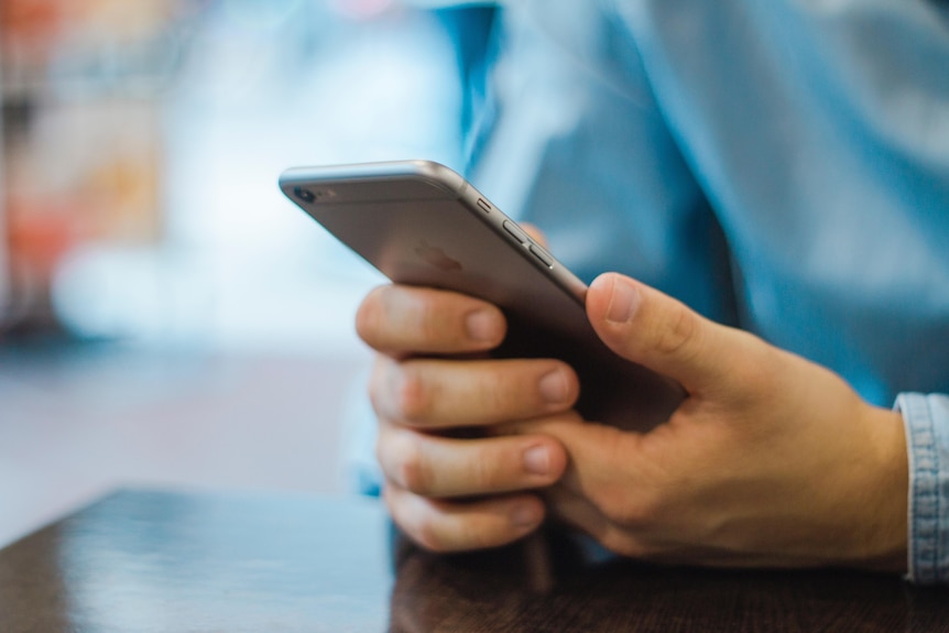 A person holds their smartphone in both hands.