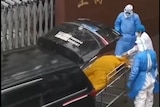 Shanghai Xinchangzheng Welfare Hospital workers in full protective clothing check yellow body bag.