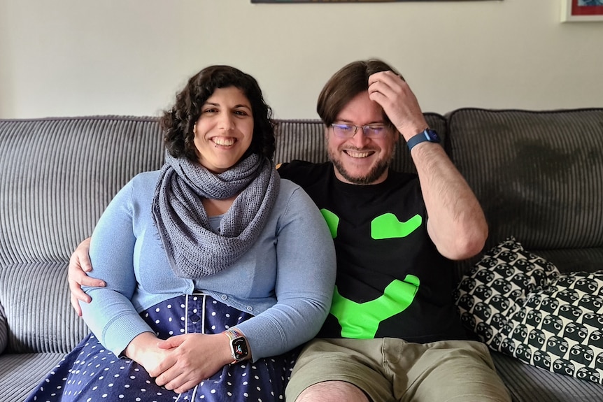 Wren Brier and partner Tim Dawson smiling on their couch