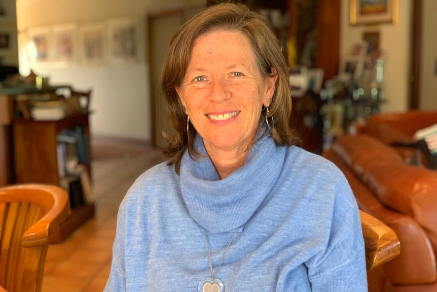 Helen Roberts sits in a dining chair wearing a blue jumper