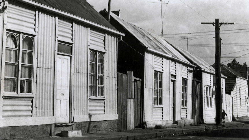 A black and white photo of corrugated iron homes.