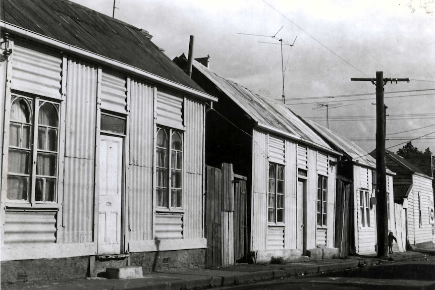 A black and white photo of corrugated iron homes.