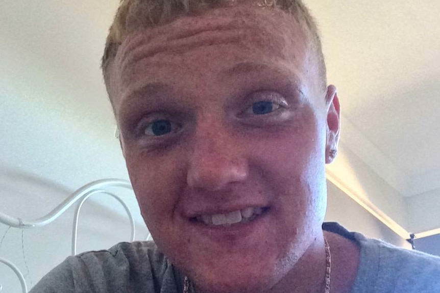 Close-up of freckle-faced young man staring at camera.