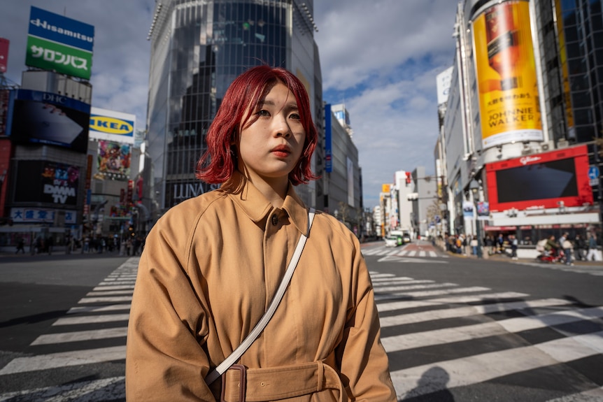 A young woman with vibrant hair walks through Tokyo
