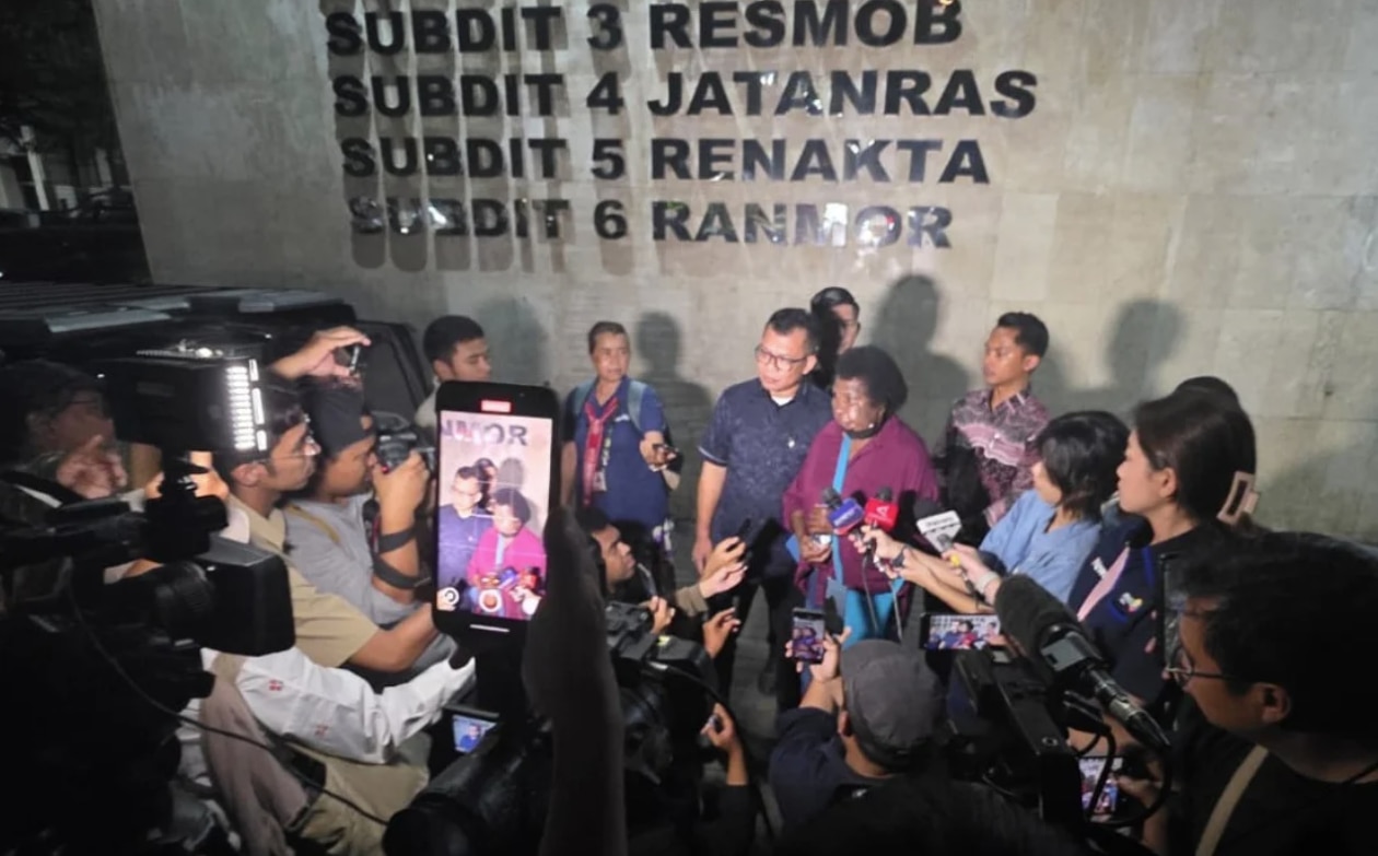 The woman in the magenta shirt and the man in the navy shirt were surrounded by journalists with microphones and cameras.
