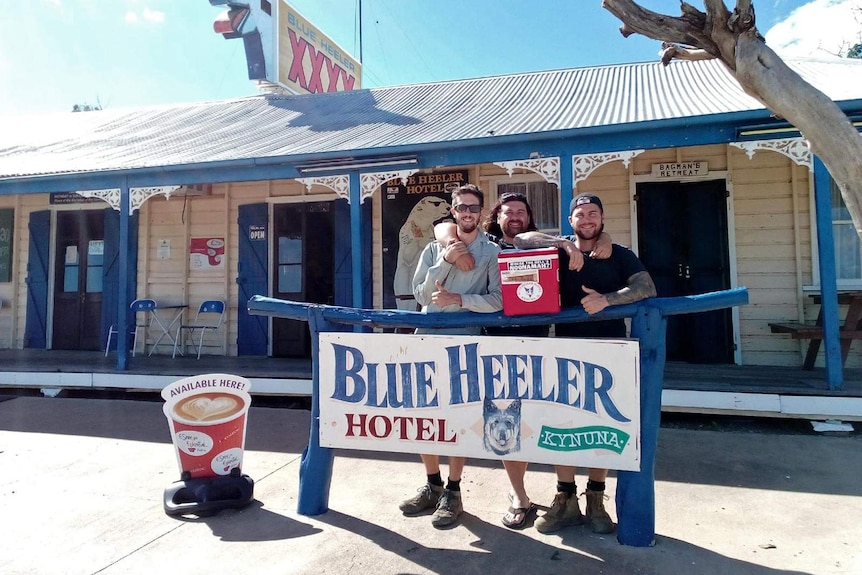 Three men stand outside with an esky the Blue Heeler Hotel in Kynuna in western Queensland.