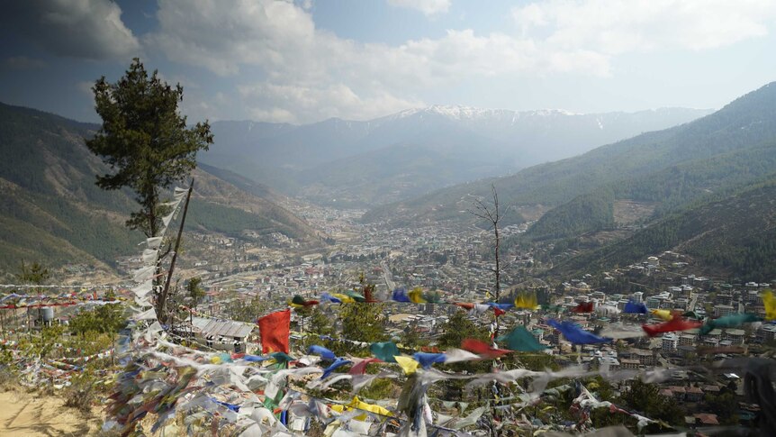 A view of a small mountainside city with colourful prayer flags in the foreground