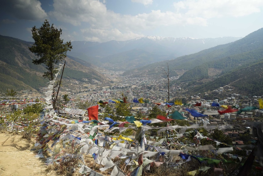 A view of a small mountainside city with colourful prayer flags in the foreground